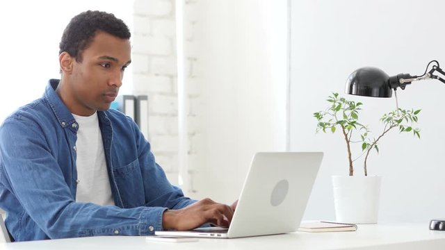 Afro-American Man Typing On Laptop in Office