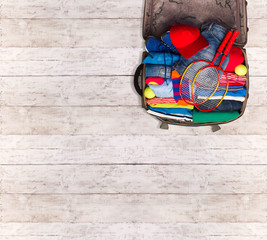 Packing a luggage for a new journey on blue wooden floor. Place for your text. 