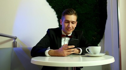 Young man in a black suit using a smartphone