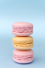 Three sweet colorful macaroons on blue table background.