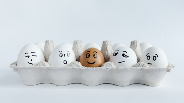 Eggs with funny faces in the package on a white background. Easter Concept Photo. Faces on the eggs