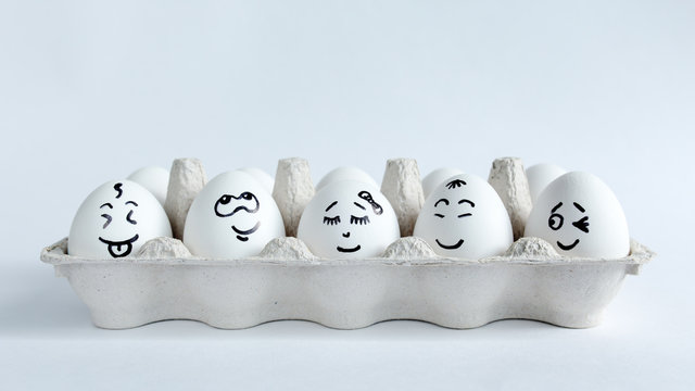 Eggs with funny faces in the package on a white background. Easter Concept Photo. Faces on the eggs