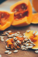 Cut pumpkin with seeds on wooden background