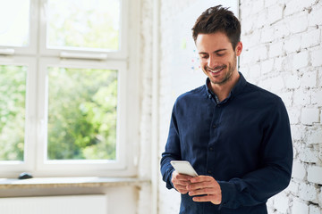 Happy young man using his smartphone at office