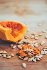 Cut pumpkin with seeds on wooden background