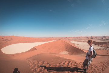 Tourist walking on the scenic dunes of Sossusvlei, Namib desert, Namib Naukluft National Park, Namibia. Afternoon light. Adventure and exploration in Africa.