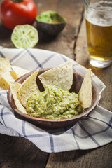 Homemade guacamole with corn nachos and a glasses of beer