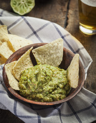 Homemade guacamole with corn nachos and a glasses of beer