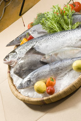 mix fresh fish on bamboo round tray with fresh vegetables with ice on brown background