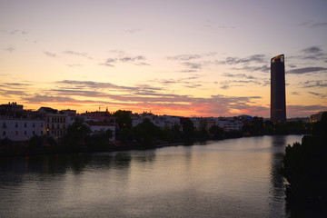 Fototapeta na wymiar Sevilla Tower along the banks of the Canal de Alfonso XIII at sunset in Seville, Andalusia, Spain