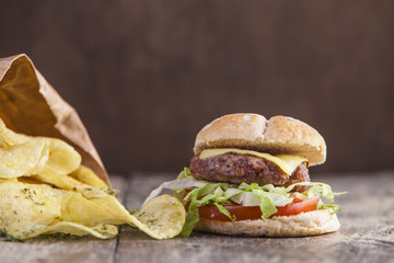 Homemade beef burger with tomato, lettuce and cheddar cheese on a wooden table 
