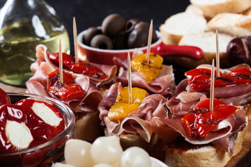 Spanish tapas with slices jamon serrano and grilled pepper. Also olives, salami, pickled onions, and peppers stuffed with cheese