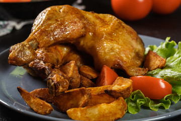 Roasted chicken legs with potato wedges and tomatoes