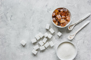 lumps of white and brown sugar on gray table background top view mock up