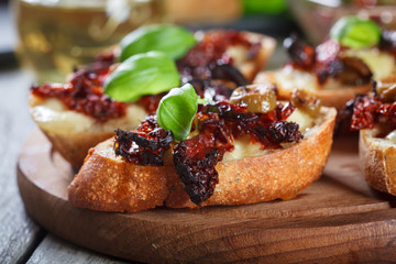 Appetizer bruschetta with sun-dried tomatoes, olives and mozarella.