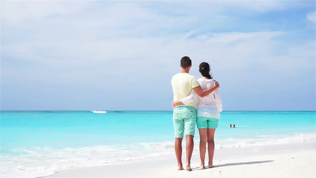 Young couple on white beach during summer vacation. Happy lovers enjoy their honeymoon. SLOW MOTION VIDEO.