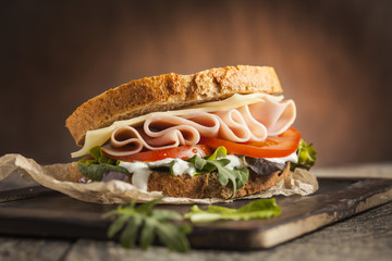 Fototapeta Tasty sandwich with ham, cheese, tomato and lettuce on wooden background obraz