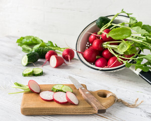 Young radishes and fresh cucumber slices on the kitchen table