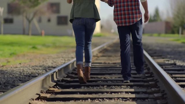 Closeup Of Couple's Feet As They Dance Along Train Tracks, Camera Tilts Up As They Walk Down Tracks, Man Twirls His Girlfriend
