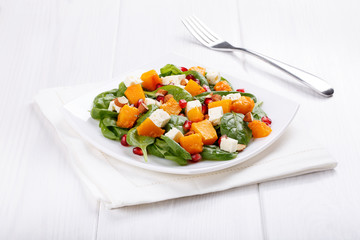Salad of spinach leaves, baked pumpkin and feta cheese with almonds and pomegranate seeds