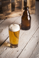 Bottle and glass of beer with wooden background