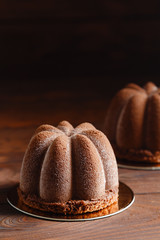 Chocolate mousse pastry dessert covered with chocolate velour on wooden background. Modern european cake. Shallow focus