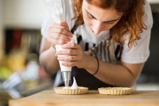Woman putting cream on tarts