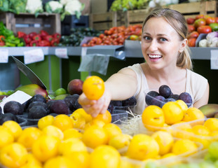 young woman buying plums at market.