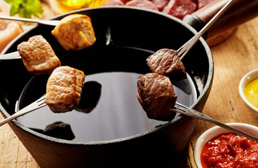 Chicken and beef cubes over pot of oil