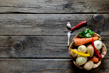 Basket with fresh vegetables on old wooden table. Space for text.