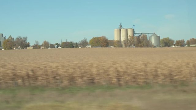 People on road trip across the united states traveling in Minnesota driving on highway through agricultural countryside past huge steel and concrete grain silos and corn fields on sunny autumn day
