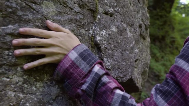Closeup Of Young Woman Touching A Mossy Cliffside As She Walks Through Temperate Rainforest