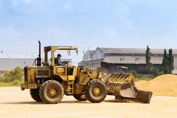 Obraz premium worker is driving a tractor to sweeping paddy rice seeds on the ground after finished drying process outside the rice mill in Ayutthaya, Thailand. agriculture industry.