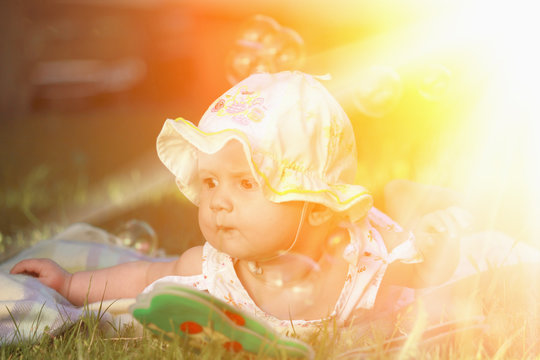 Beautiful baby girl lying on the grass. Nature, holidays, childhood concept.