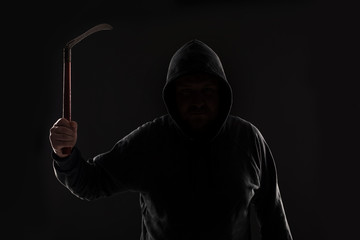 Criminal in dark clothes and balaclava with scythe