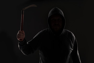 Criminal in dark clothes and balaclava with scythe