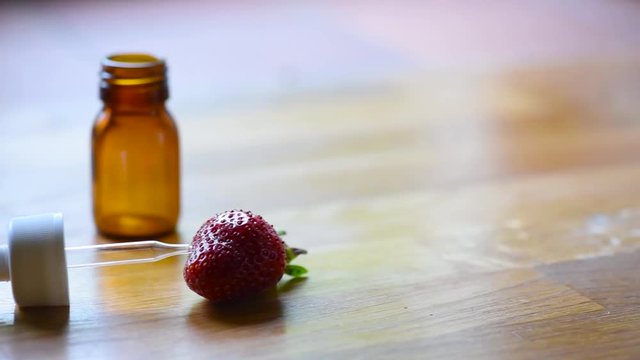 Pipette, medical bottle and strawberry on a wooden table