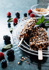 Peanut chocolate butter ice cream popsicles on dark marble table with fresh summer berries. Selective focus, top view, free text space.