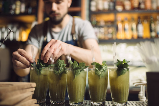 Young Male Bartender Preparing Many Mochito At A Bar Counter