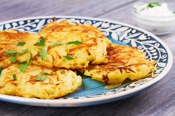 Potato Pancakes With Yogurt Sauce. Vegetable fritters. Latkes on blue plate
