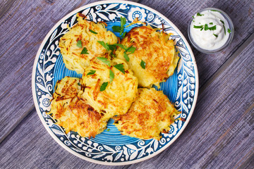 Potato Pancakes With Yogurt Sauce. Vegetable fritters. Latkes on blue plate. View from above
