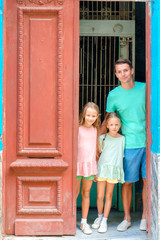 Portrait of happy family looking out door at old apartments in Havana