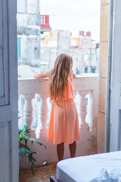 Little girl on old balcony in apartment looking on the street in Old Havana, Cuba.