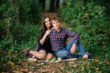 beautiful couple sitting in the woods on a picnic kiss happy hug green trees, nature, apples, plaid