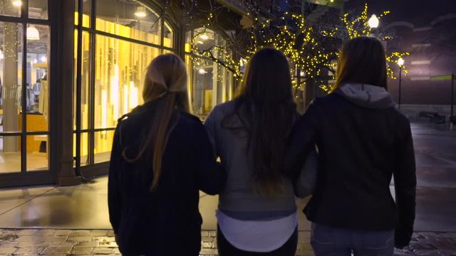 Girls Walk Away From Camera, Past Shop With Cool Light Display Inside, Blonde Points To It