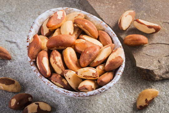 Bowl of peeled brazil nuts on stone background closeup