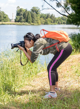 Woman photographs on the shore of the pond