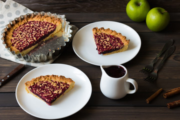 Pie with apple and berry jam on a dark wooden background