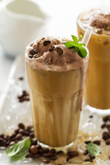 Tasty cold refreshing drink with coffee, milk, chocolate ice cream and ice in glass on ice background. Closeup.
