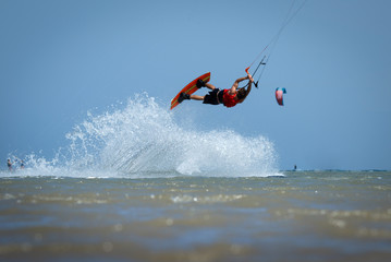 Recreational water sports: kite surfing. Kite boarding sportsman jumping high in the sky on windy day